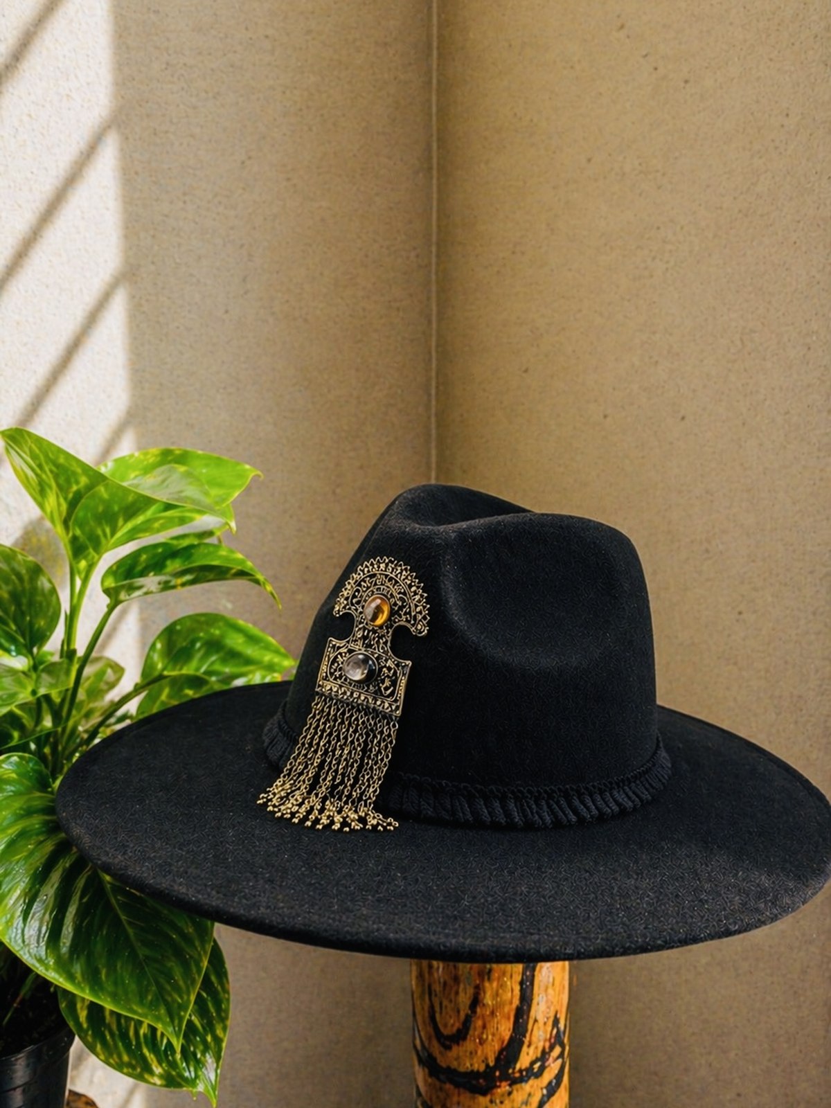 Black fedora with ornate gold pendant and tassel fringe