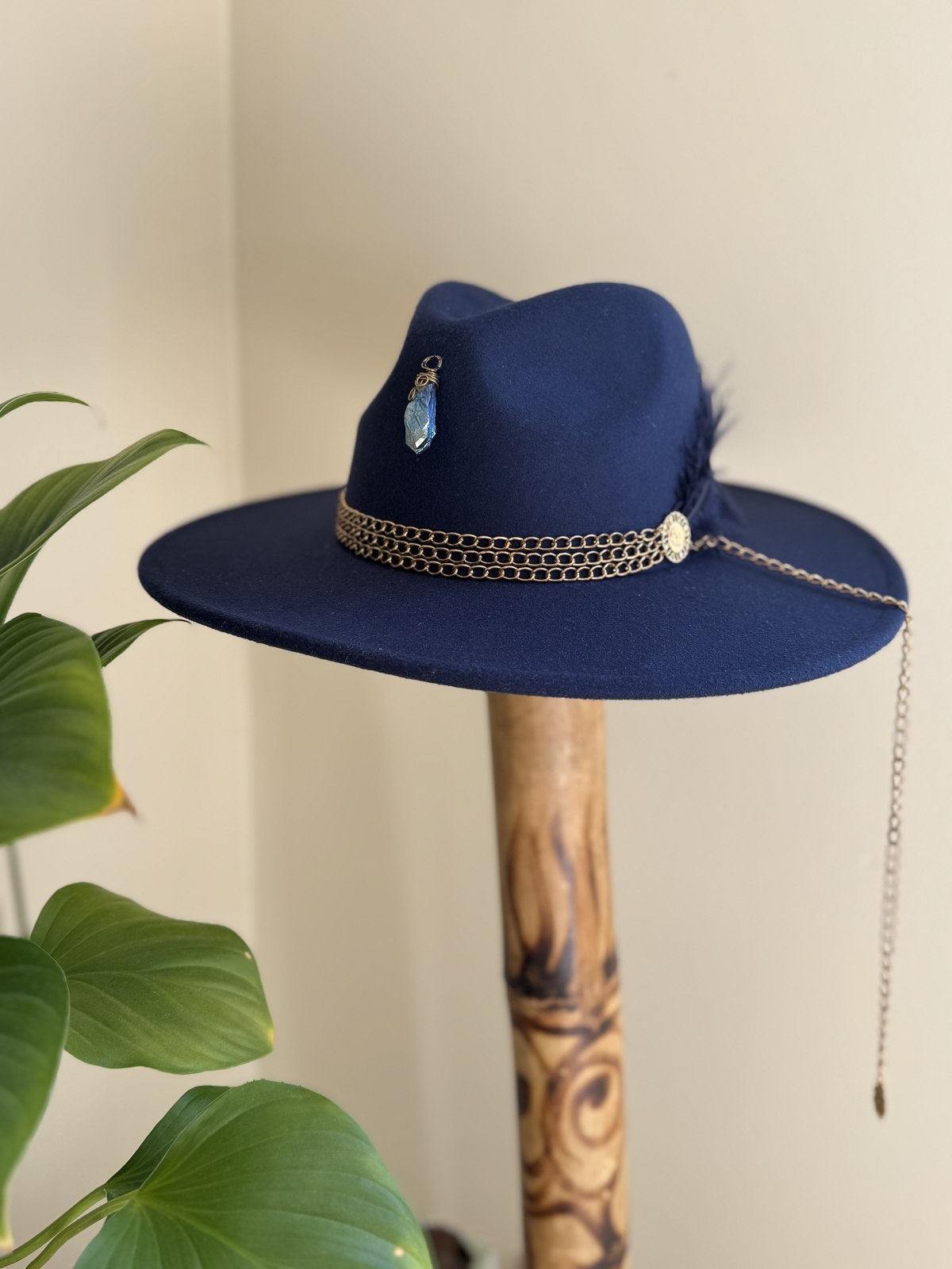 Navy fedora with gold chain band and wire-wrapped stone pendant